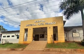 Fachada del Hospital Distrital de Presidente Franco, edificio amarillo con escaleras y nombre en letras metálicas plateadas, entorno con vegetación.