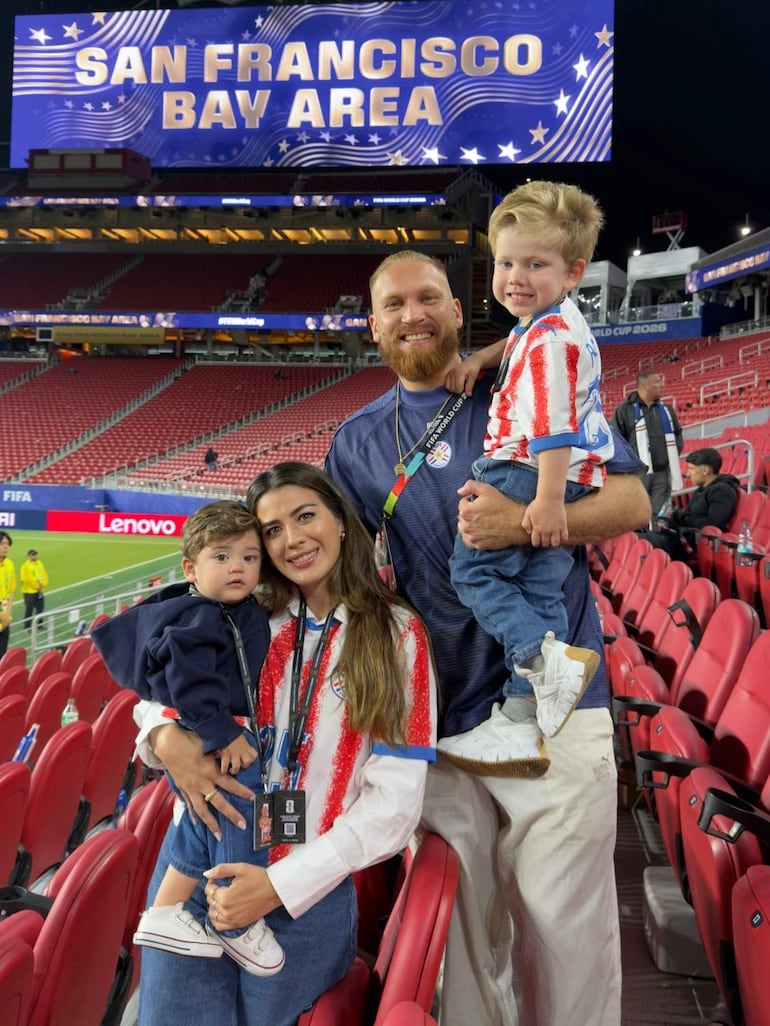 Isidro Pitta sonríe junto a una mujer en camiseta blanca y dos niños entre abrazos en un ambiente festivo en el estadio.