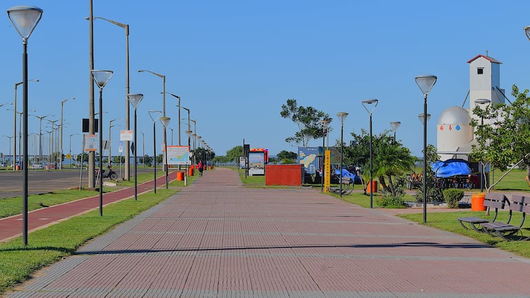 Paseo peatonal iluminado con faroles y bancos, en un ambiente tranquilo y soleado en Encarnación.