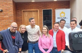 Manuel Aguilar con chaqueta roja, Santiago Peña en el centro y Johana Vega a su lado, todos sonrientes frente a un cartel de HOGAR.py.