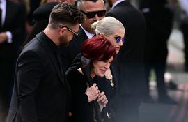La familia de Ozzy Osbourne, su hijo Jack Osbourne (izq.), la ventana Sharon Osbourne (centro) y su hija Kelly Osbourne (der.) llegan para depositar flores en el banco del puente Black Sabbath en Broad Street durante la procesión fúnebre por Ozzy Osbourne, el fallecido vocalista de Black Sabbath, en Birmingham, centro de Inglaterra, el 30 de julio de 2025.