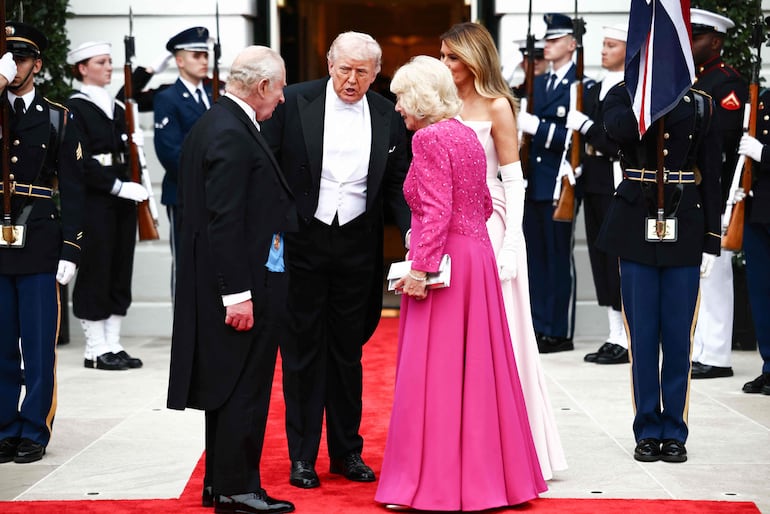 Melania Trump y Camila con sus elegantes maxivestidos, junto a sus esposos, antes de ingresar a la cena de Estado en la Casa Blanca. (Henry NICHOLLS / AFP)