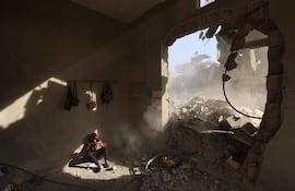 Un niño palestino lee un libro entre los escombros de una casa destruida por un bombardeo israelí en el campo de refugiados de Nuseirat, en el norte de la Franja de Gaza, en marzo de este año.