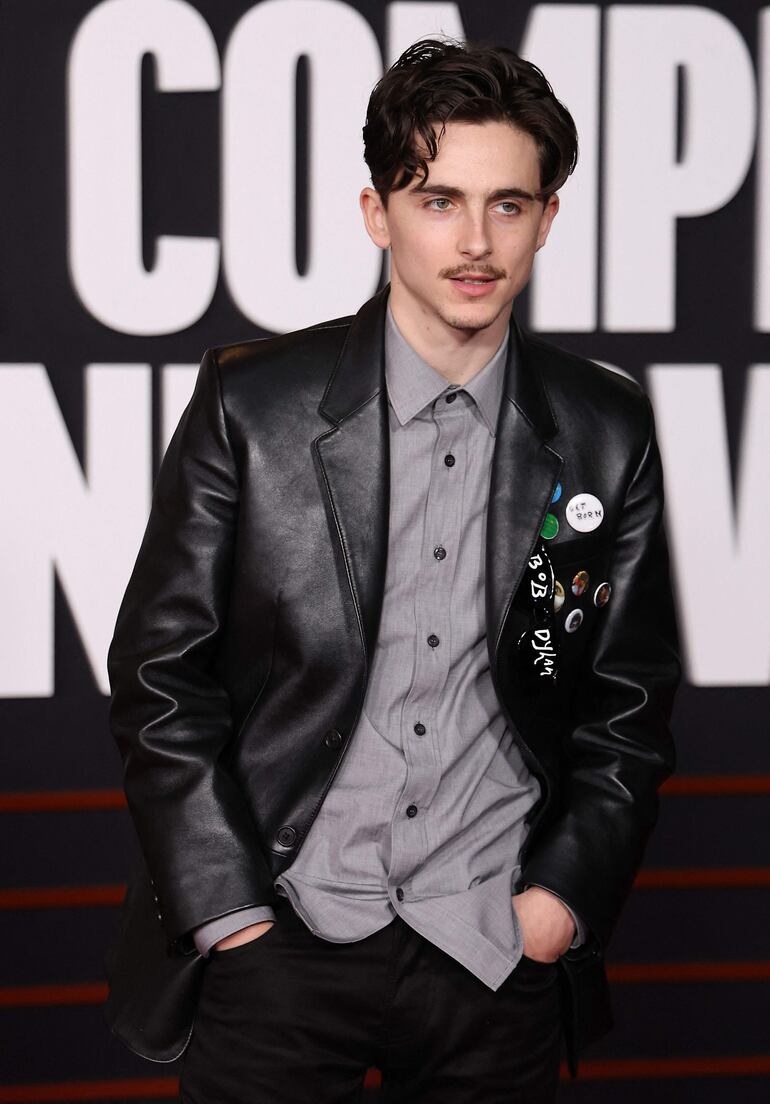Timothée Chalamet luciól una chaqueta de cuero de Prada y en la solapa varios pines en homenaje a Bob Dylan. (Michael Tran / AFP)