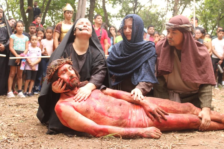 La madre de Jesús, con el rostro marcado por el dolor y la angustia, contempla a su hijo. Sus manos temblorosas y su mirada llena de amor y tristeza reflejan el peso de un sufrimiento que trasciende lo humano.