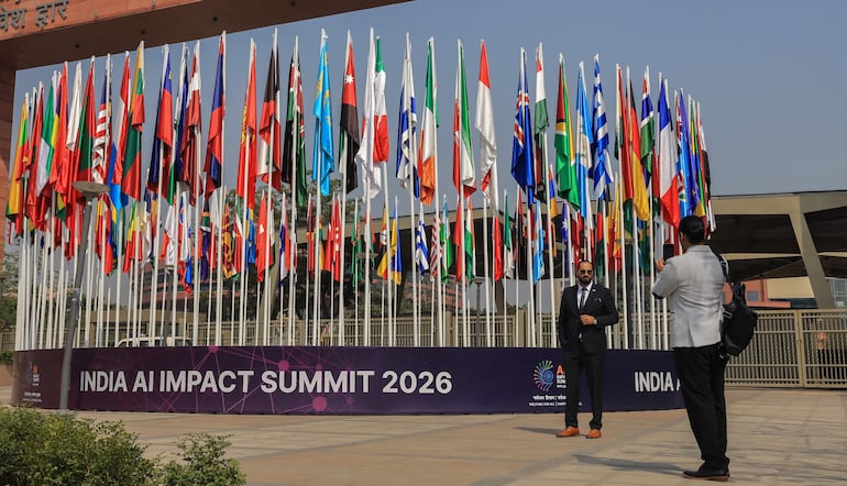Visitantes toman fotografías junto a las banderas de los países participantes frente al recinto de la AI Impact Summit 2026, en el Bharat Mandapam, en Nueva Delhi, India, el 16 de febrero de 2026.