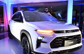 El SUV Chevrolet Sonic en primer plano, iluminado con luces azules y rosas, mientras dos personas exploran el vehículo.