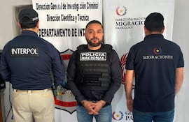 Hombres en chalecos de policía y migraciones en conferencia, con carteles de instituciones visibles en el fondo.