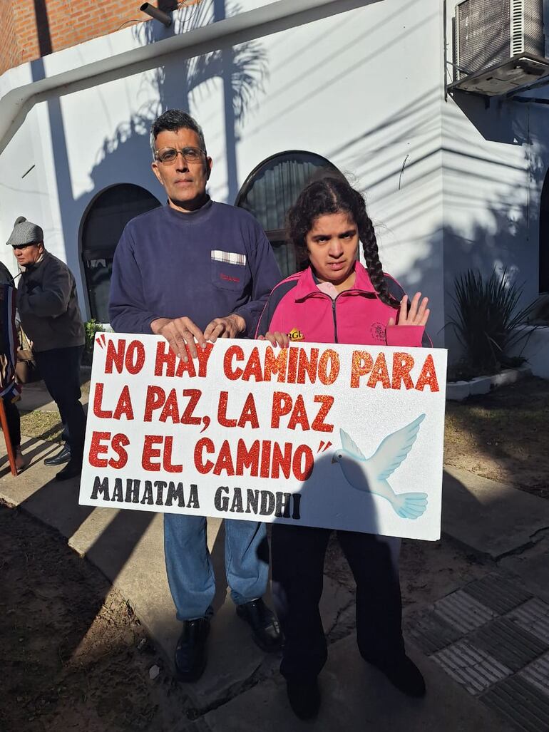 Don Jorge Riveros y su hija María Teresita (16), diagnosticada con autismo y retraso mental portando un cartel.