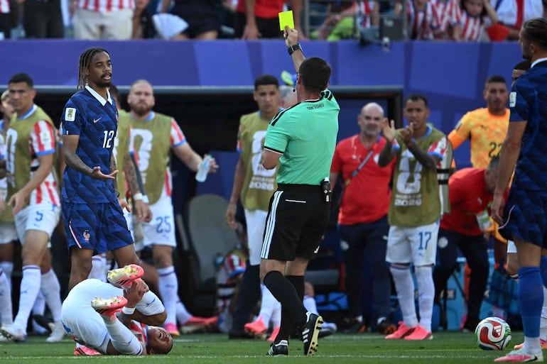 El árbitro uzbeko Ilgiz Tantashev muestra una tarjeta amarilla al delantero de Francia Bradley Barcola ante la mirada del defensa de Paraguay Juan José Cáceres durante el partido de fútbol de los octavos de final de la Copa Mundial 2026 entre Paraguay y Francia en el Philadelphia Stadium en Filadelfia.