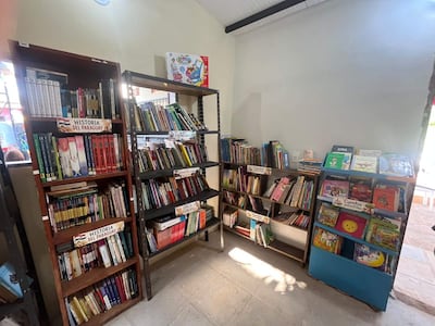Estanterías llenas de libros sobre historia y educación en una biblioteca iluminada con paredes claras y suelo de cerámica.