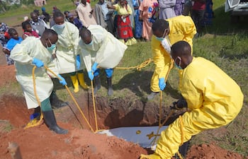 Trabajadores sanitarios entierran el ataúd de víctimas del brote de ébola en el cementerio de Nyamurongo, en Bunia.