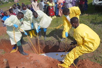 Trabajadores sanitarios entierran el ataúd de víctimas del brote de ébola en el cementerio de Nyamurongo, en Bunia.