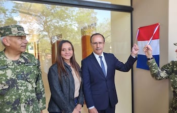 Cinco personas en evento inaugural con bandera paraguaya: generales en uniforme y una mujer sonriente en chaqueta negra.
