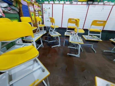 Aula con sillas amarillas desordenadas y piso mojado, mostrando el impacto del temporal en el ambiente escolar.
