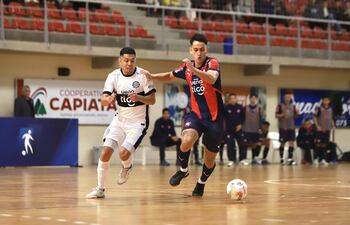 El goleador Diego Poggi avanza ante la presencia del franjeado Hugo Martínez, en el juego semifinal de ida, que ganó Cerro Porteño, el sábado. (Foto APF)