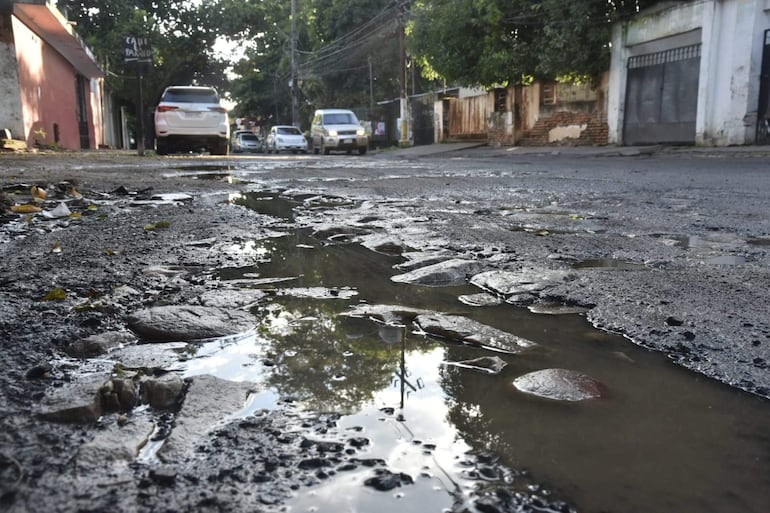 Calle pavimentada en Santa Rosa, autos visibles, agua estancada y hojas caídas alrededor.