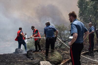 Agentes de policía ayudan a los lugareños a apagar un incendio forestal que se acerca a casas en Palermo, Sicilia, sur de Italia, el 25 de julio de 2023. Los incendios forestales han arrasado Sicilia en medio de la última ola de calor de Italia y el aeropuerto de Palermo estuvo cerrado brevemente al tráfico en la mañana del 25 de julio.
