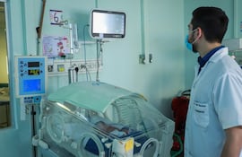 Un médico observa a un bebé con virus sincitial en cuidados intensivos.