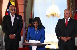 La presidenta Delcy Rodriguez (C) promulga la histórica ley de aministía para presos políticos en Venezuela. La acompañan el presidente del Parlamento y su hermano, Jorge Rodríguez (i) y ministro del Interior, Diosdado Cabello.