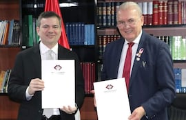 José Duarte Penayo y Emilio Rolón sostienen documentos durante un acto en una oficina oficial.
