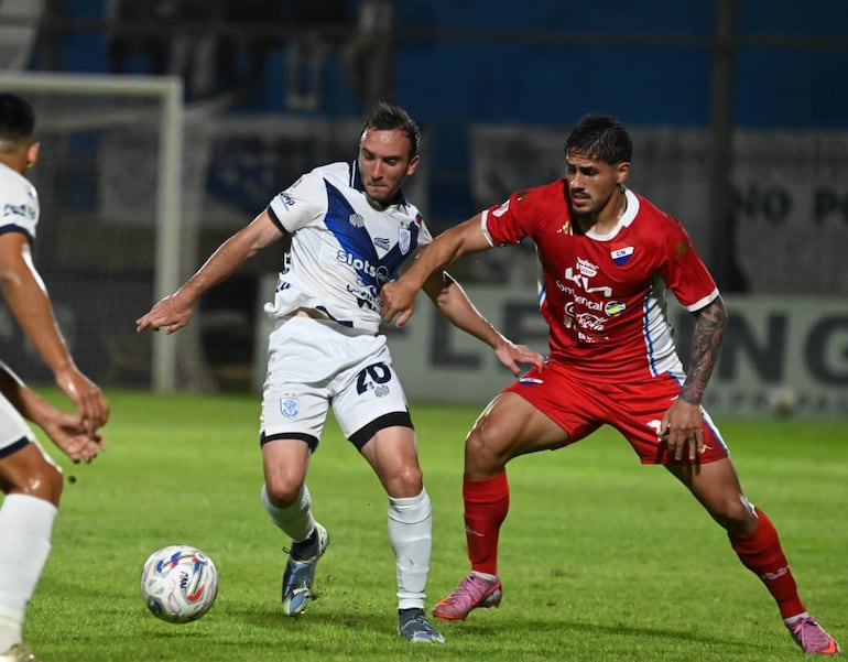 El mediocampista del Sportivo Ameliano, Valentín Larralde transporta el esférico ante la marca del volante de Nacional, Roberto Ramírez.