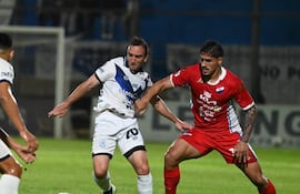 El mediocampista del Sportivo Ameliano, Valentín Larralde transporta el esférico ante la marca del volante de Nacional, Roberto Ramírez.