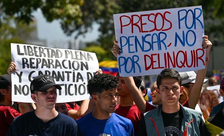 Una mujer sostiene una pancarta que dice "Presos por pensar, no por delinquir" mientras estudiantes universitarios, opositores al gobierno, marchan durante el Día de la Juventud en Caracas el 12 de febrero de 2026. 