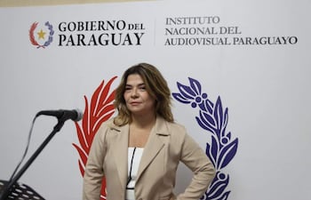 Natalia Fuster Cascio con chaqueta beige y blusa blanca, de pie frente a un fondo institucional del Gobierno del Paraguay.