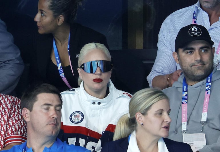 Lady Gaga (con lentes) y su prometido Michael Polansky (con gorro) observan la competencia de natación en la Arena Paris La Defense.