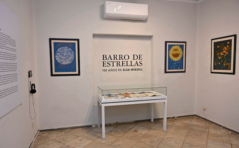 Exposición tranquila en galería con obras de arte y vitrina blanca, destacando el evento de Elsa Wiezell.