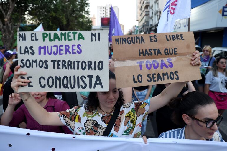 Una mujer sostiene carteles durante una marcha como parte del Día Internacional de Eliminación de la Violencia contra la Mujer este martes, en Asunción.