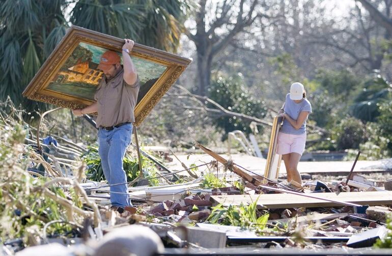 Charles Graham (i) ayuda a su novia Vicky Barrett (d) a recuperar pinturas de lo que queda de su casa en Gulfport, Misisipi, después de que el huracán Katrina la destruyera el martes 30 de agosto de 2005.