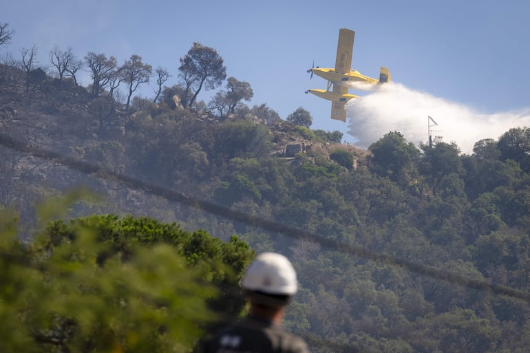Una avioneta del servicio de Bomberos arroja agua sobre una colina próxima a la localidad de Calonge tras el incendio forestal que comenzó ayer en La Bisbal de l'Empordà (Girona). Europa se ve azotada por una ola de calor extremo. España sufre graves incendios.