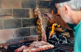 Hombre adulto cocina asado de costilla chorizos a la parrilla