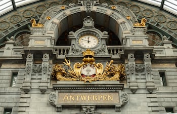 Primer plano de la decoración del reloj y los símbolos en el edificio de la estación central de Amberes, Bélgica.