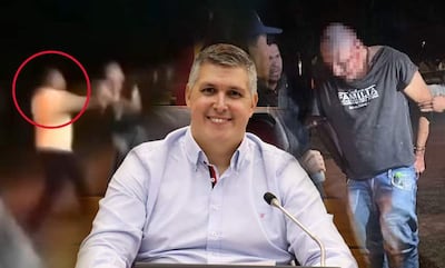 Hombre sonriente con camisa clara en primer plano, un grupo de personas interactuando en un ambiente exterior.