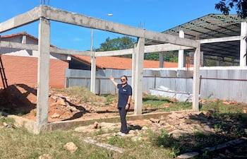 Lucy Giménez en camiseta oscura y pantalones, señalando área de construcción en terreno despejado con estructuras en obra.