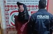 Hombre encapuchado entre policías en sede de investigación, uno lleva chaqueta marcada con 'POLICÍA INVESTIGACIONES'.
