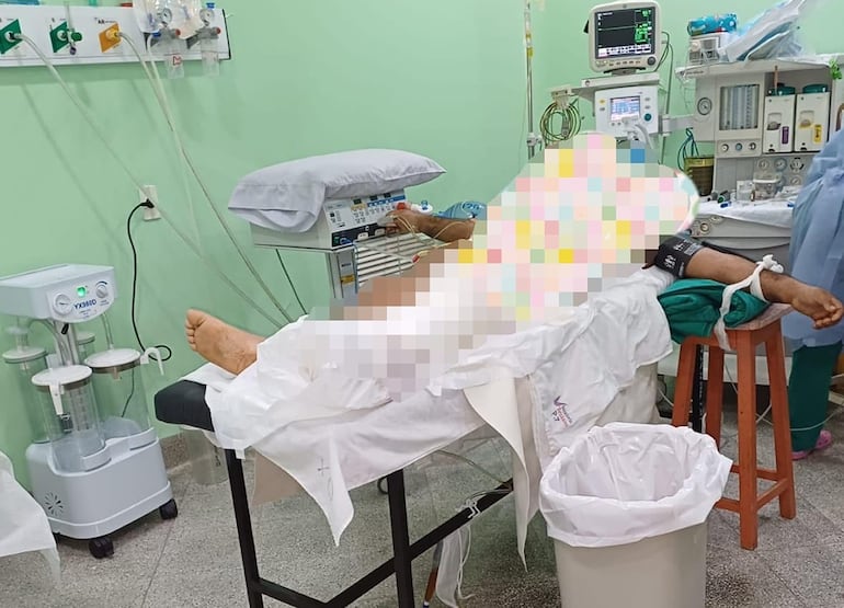 Un paciente en pleno procedimiento quirúrgico sobre una simple camilla y butacas de madera como reposabrazos en el Instituto de Medicina Tropical. 