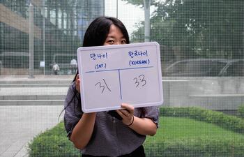 La trabajadora Kim Jin-sil muestra en un panel cuántos años menos tiene según la nueva legislación de Corea del Sur. (AFP)