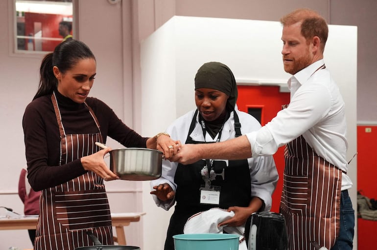 Meghan y Harry cocinan durante una visita a Himmah Hub, una organización benéfica de Nottingham que combate la pobreza, la inseguridad alimentaria, el racismo y la exclusión social mediante comidas comunitarias, la entrega de paquetes de alimentos y otras formas de apoyo práctico. (Annabel Lee-Ellis / POOL / AFP)