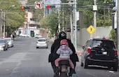 Un adulto conduce una motocicleta con una niña pequeña como pasajera.
