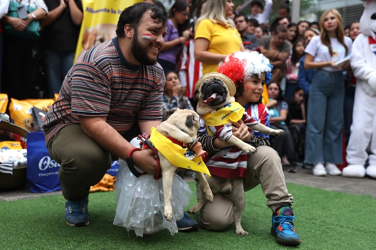 Personas posan con sus mascotas en el desfile de la celebración del Jagua Patriotaeste jueves, en Asunción (Paraguay).