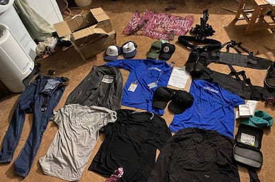 Colección de prendas, incluyendo camisetas y pantalones de un cellshop, dispuestas desordenadamente en el suelo.