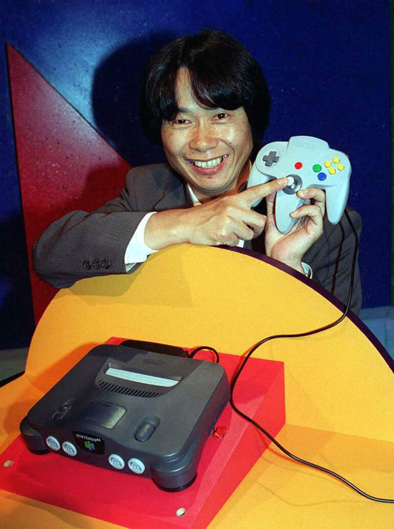 Esta foto de archivo tomada el 15 de mayo de 1996 muestra al diseñador japonés de videojuegos Shigeru Miyamoto señalando el mando del nuevo juego insignia de Nintendo 64, Super Mario 64, en la Exposición de Entretenimiento Electrónico de Los Ángeles, en California.