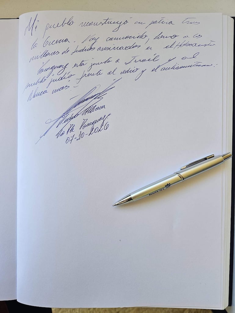 Cuaderno con página escrita a mano, bolígrafo plateado a un lado, ambiente interior claro.