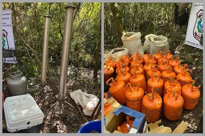 Tanques metálicos y garrafas de gas apiladas en un área boscosa sin personas visibles.