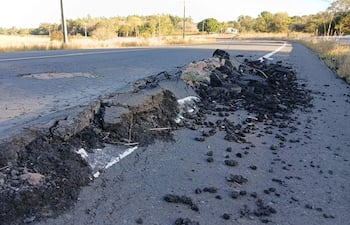 La imagen muestra un tramo de carretera dañado, con el asfalto agrietado y levantado en varias secciones. No hay personas visibles en la escena. El entorno es natural, con vegetación y árboles al fondo, sugiriendo que la ubicación es rural.
En el primer plano, el asfalto tiene secciones quebradas, con escombros y restos de material negro, indicando un posible deterioro por condiciones climáticas o un evento sísmico. La carretera parece ser de doble sentido, con un marcado de línea blanca que está parcialmente cubierto por el asfalto levantado.
No hay elementos visuales que identifiquen algún equipo de fútbol, lugar icónico o monumento reconocible. La imagen sugiere una situación que podría requerir atención, tal como reparaciones viales. No hay texto visible en la imagen.