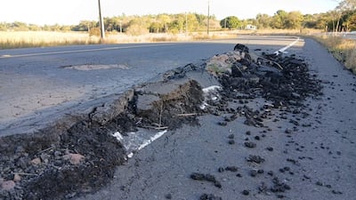 La imagen muestra un tramo de carretera dañado, con el asfalto agrietado y levantado en varias secciones. No hay personas visibles en la escena. El entorno es natural, con vegetación y árboles al fondo, sugiriendo que la ubicación es rural.
En el primer plano, el asfalto tiene secciones quebradas, con escombros y restos de material negro, indicando un posible deterioro por condiciones climáticas o un evento sísmico. La carretera parece ser de doble sentido, con un marcado de línea blanca que está parcialmente cubierto por el asfalto levantado.
No hay elementos visuales que identifiquen algún equipo de fútbol, lugar icónico o monumento reconocible. La imagen sugiere una situación que podría requerir atención, tal como reparaciones viales. No hay texto visible en la imagen.